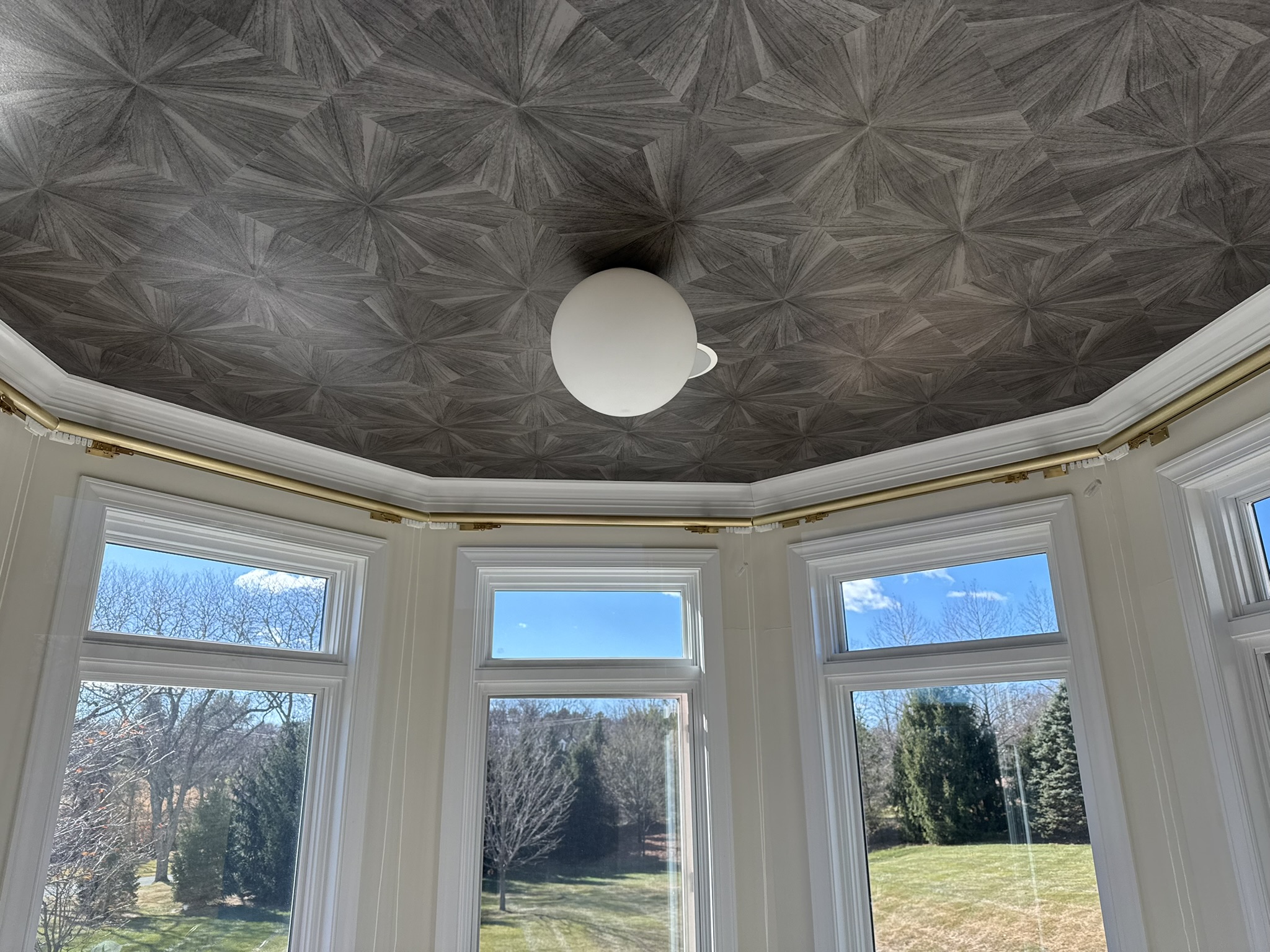 Custom gold curved drapery rod installed in octagonal bay window